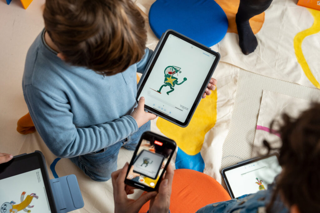 Dos chicos comparan ilustraciones digitales en tabletas y en un móvil